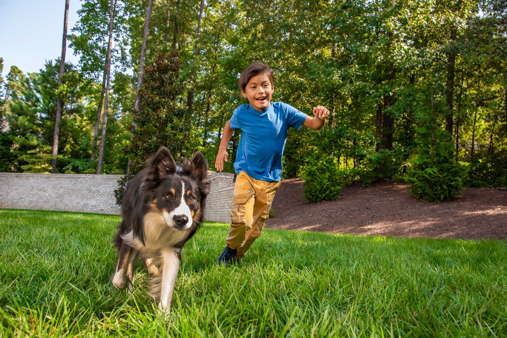 boy running with his dog in backyard_RobertHolland_Photographer_Director