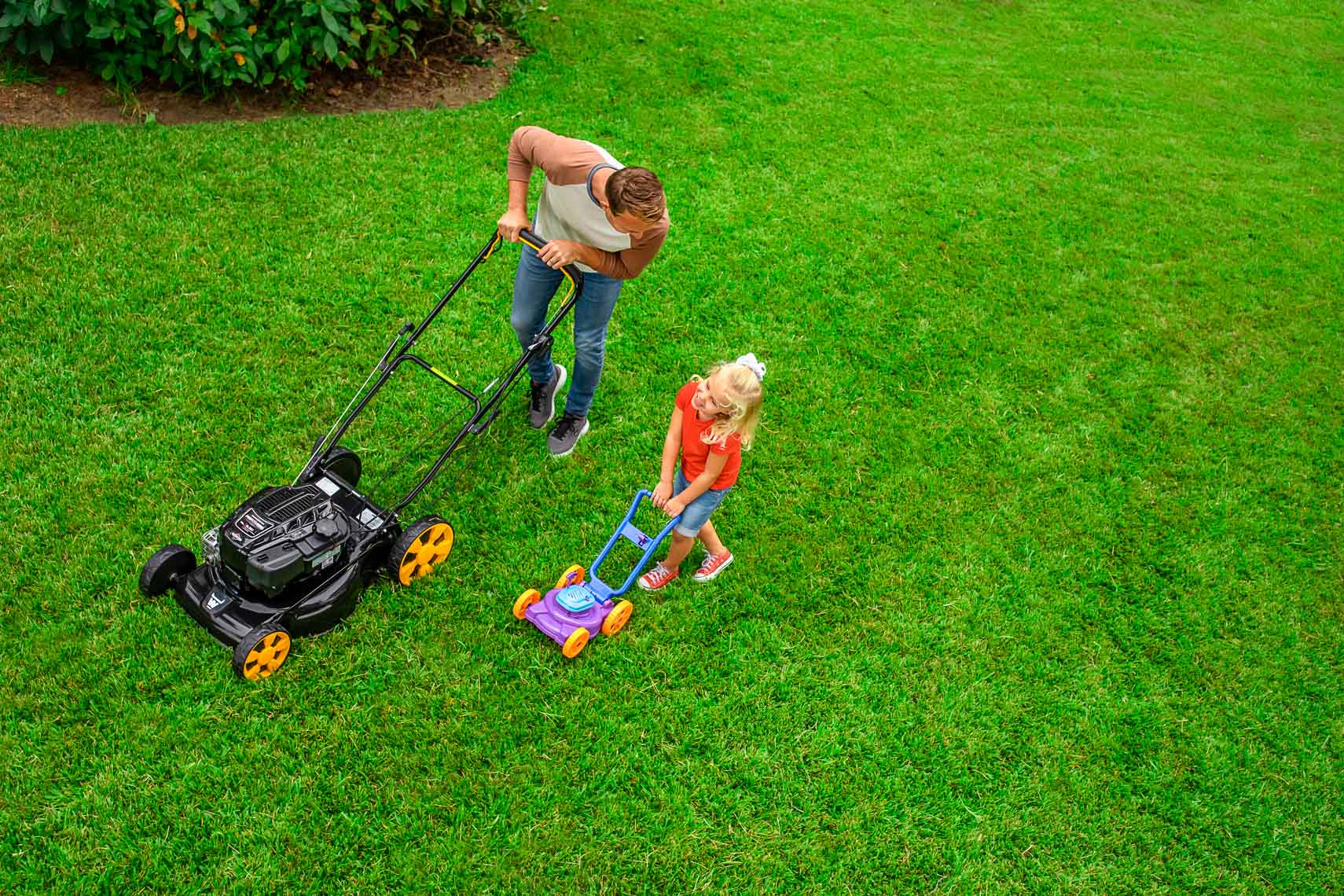 overhead view of father with lawnmower and daughter with toy lawnmower_Robert_Holland_Photographer_Director