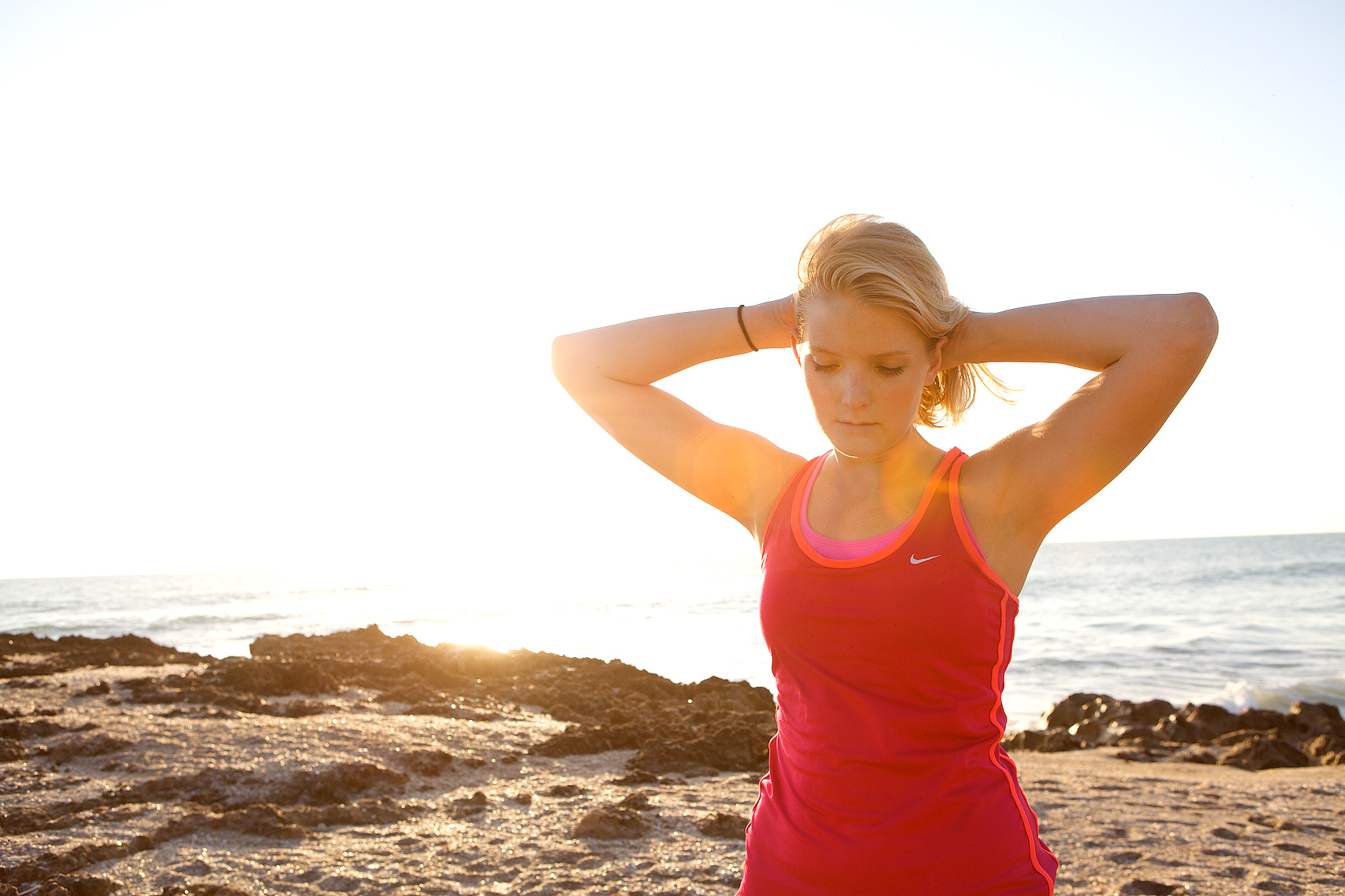 young woman runner pulls her hair back at sunrise on beach_5080_Robert-Holland.jpg