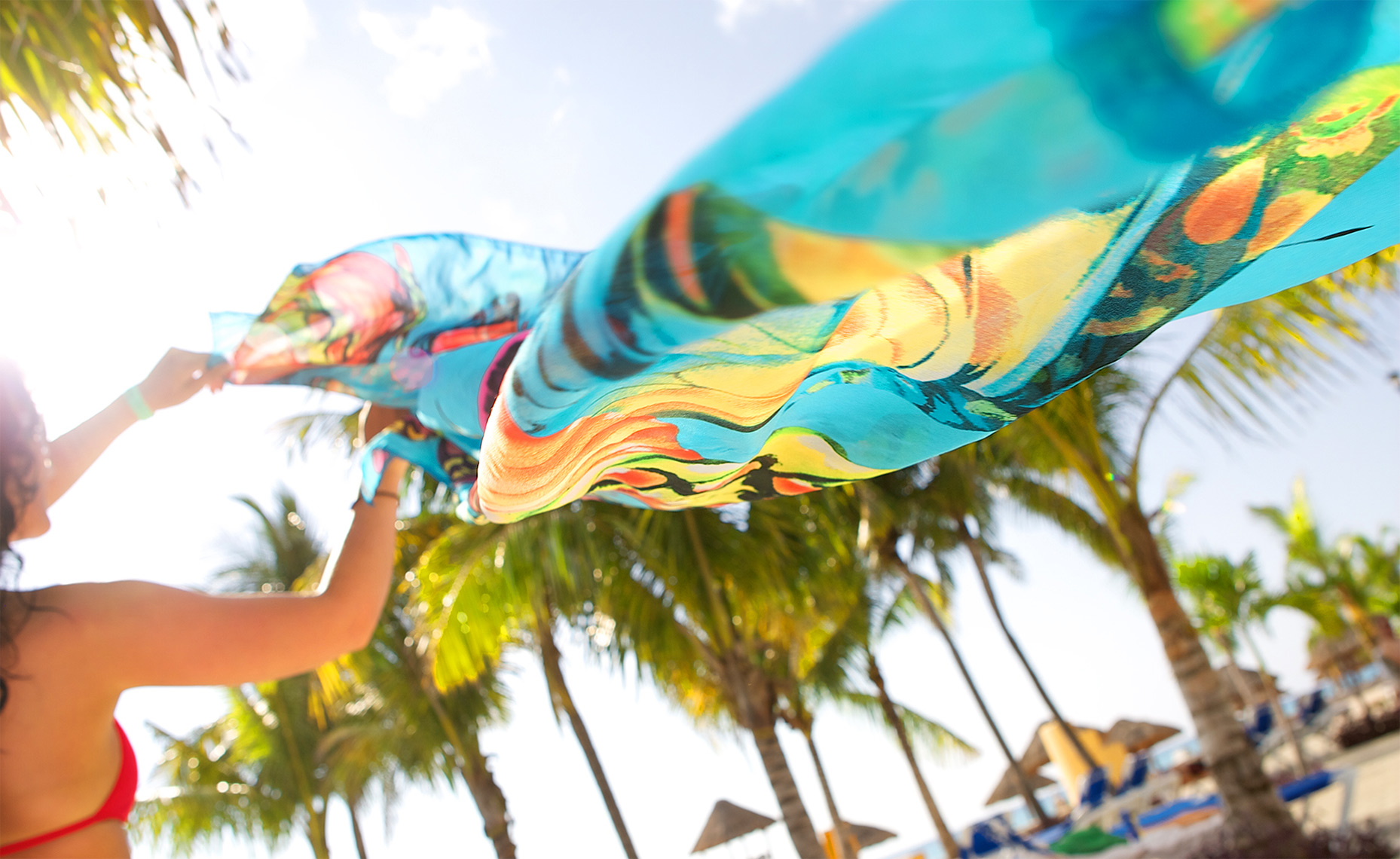 woman letting wind blow colorful fabric in the breeze, with palm trees at resort, Mexico_Holland_resort lifestyle photography